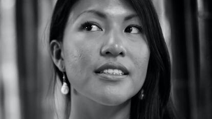 A black and white image of poet April Yee. April is wearign a white dress and her long dark hair is swept over one shoulder.