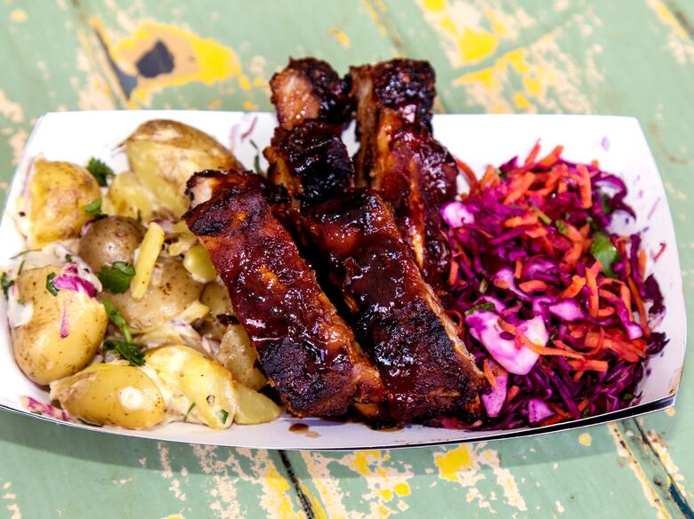 Photo of a dish of glazed ribs, potato salad and slaw served by Street Pig BBQ at Southbank Centre Food Market