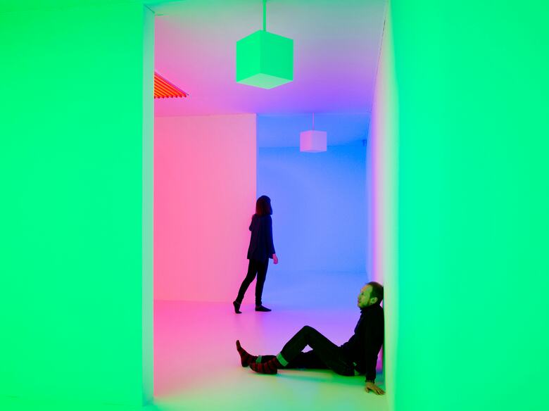 Visitors sitting and standing in Green and Pink Light Installation by artist, Carlos Cruz-Diez at Hayward Gallery