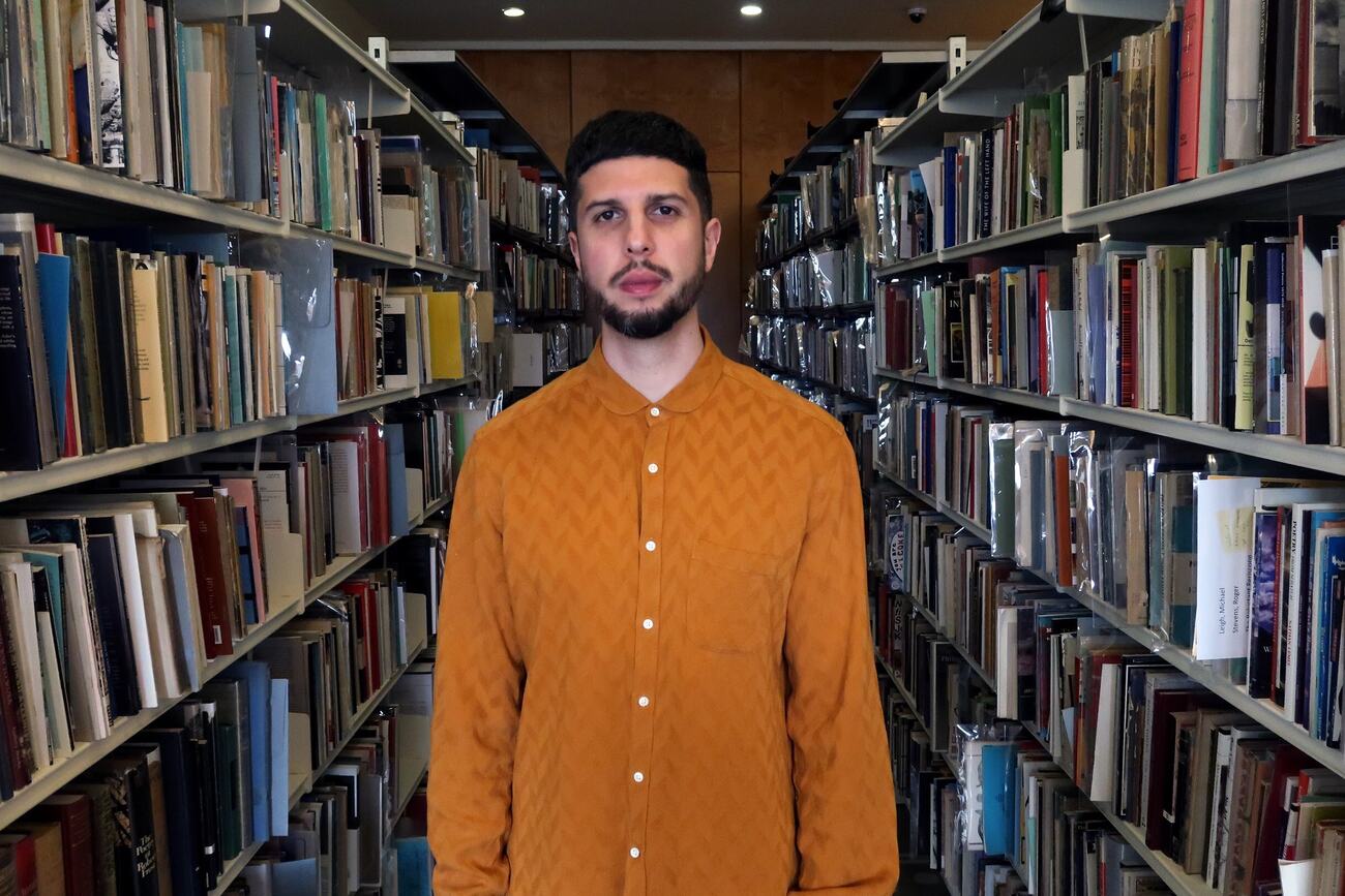 Poet Anthony Anaxagorou stands in the National Poetry Library at Southbank Centre