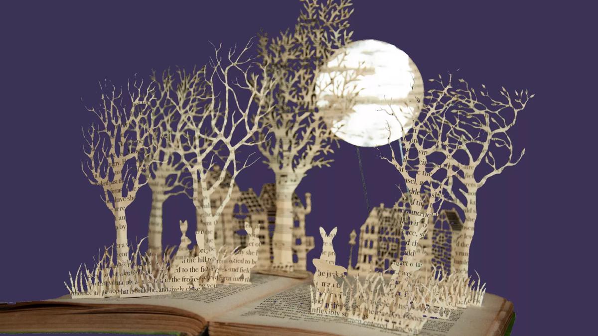 Book sculpture of hares in a forest. In the background is a view of a moon