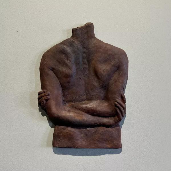 A metal sculpture of a back with arms crossed