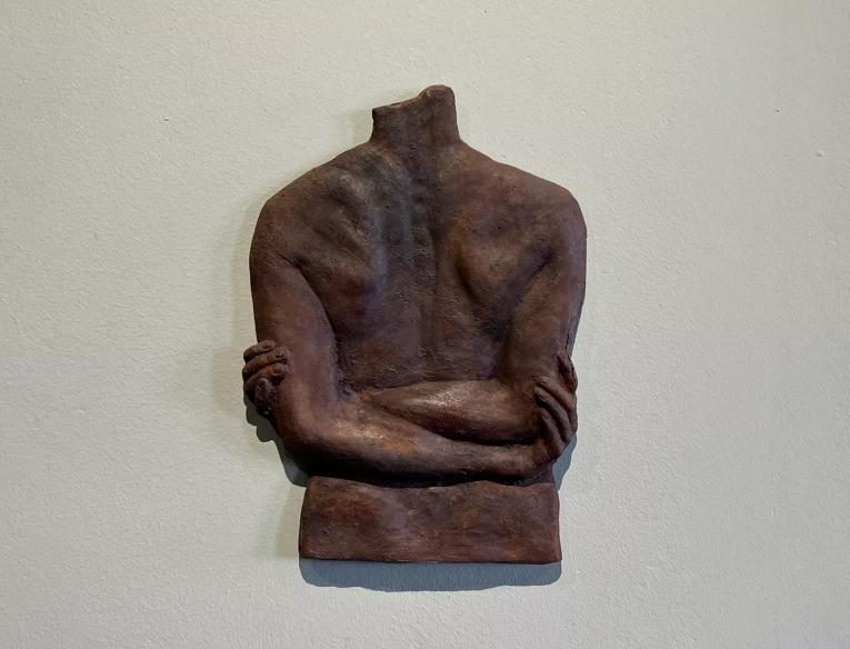 A metal sculpture of a back with arms crossed
