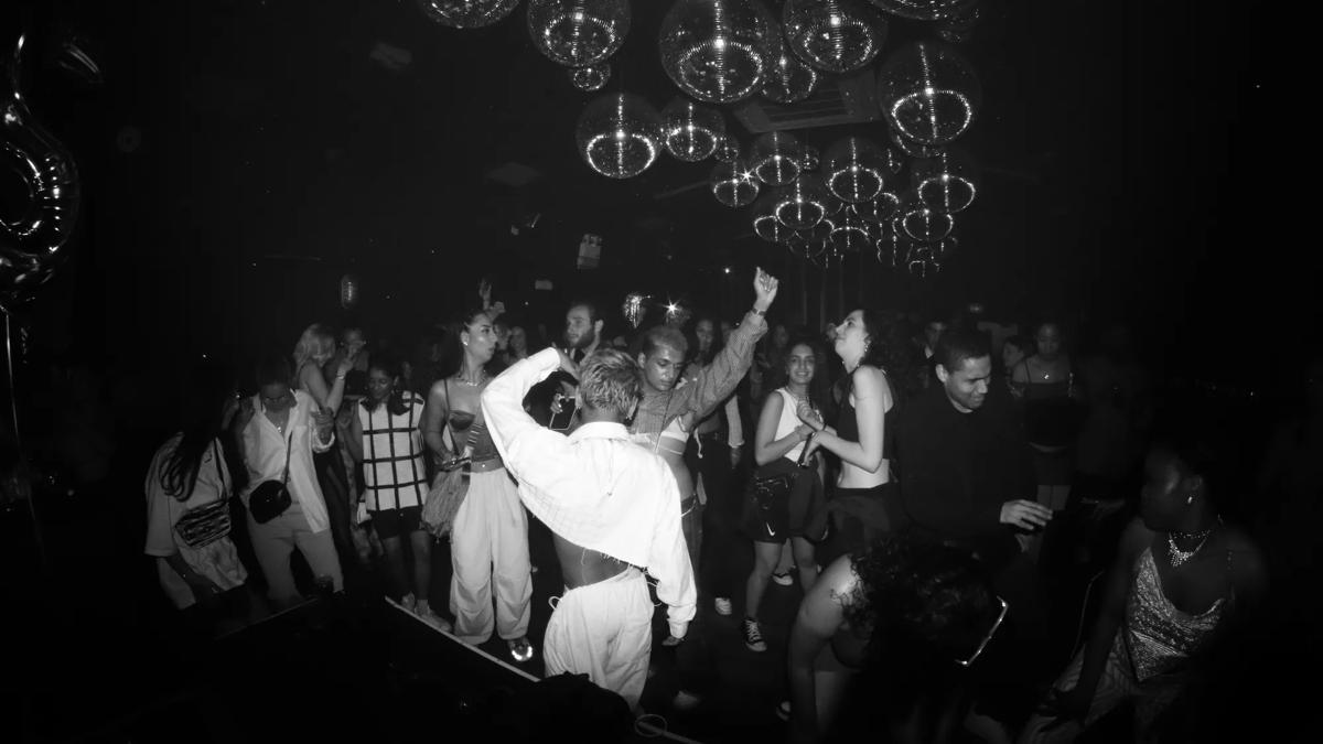 Black and white image of people dancing under several disco balls