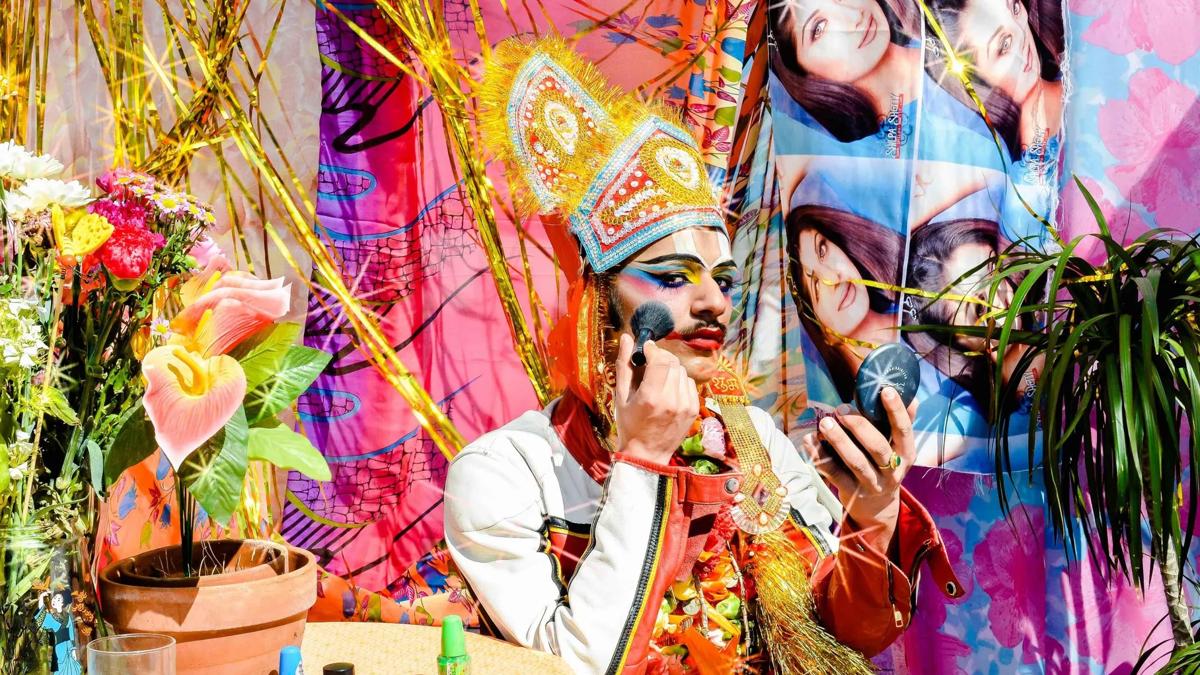 Nazar, person putting on makeup in a colourful background setting