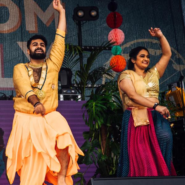 Two South Asian dancers perform on stage. 