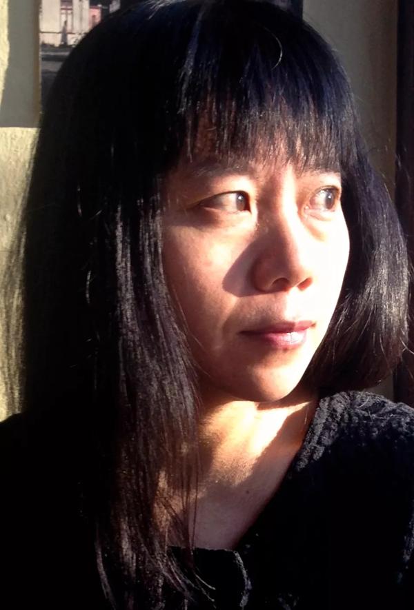 Xiaolu Guo looks off towards her left with natural light illuminating her face