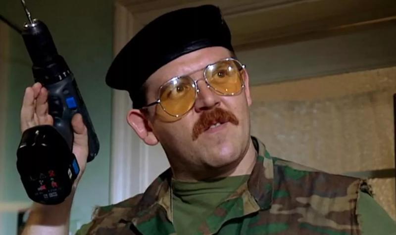 Actor Nick Frost as the character Mike Watt in Spaced; he wears sunglasses and an army beret, wears army fatigues and holds a gun
