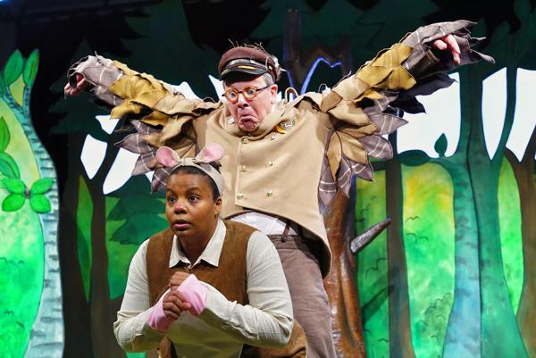 An actor dressed as a bird is standing over an actor dressed as a mouse.