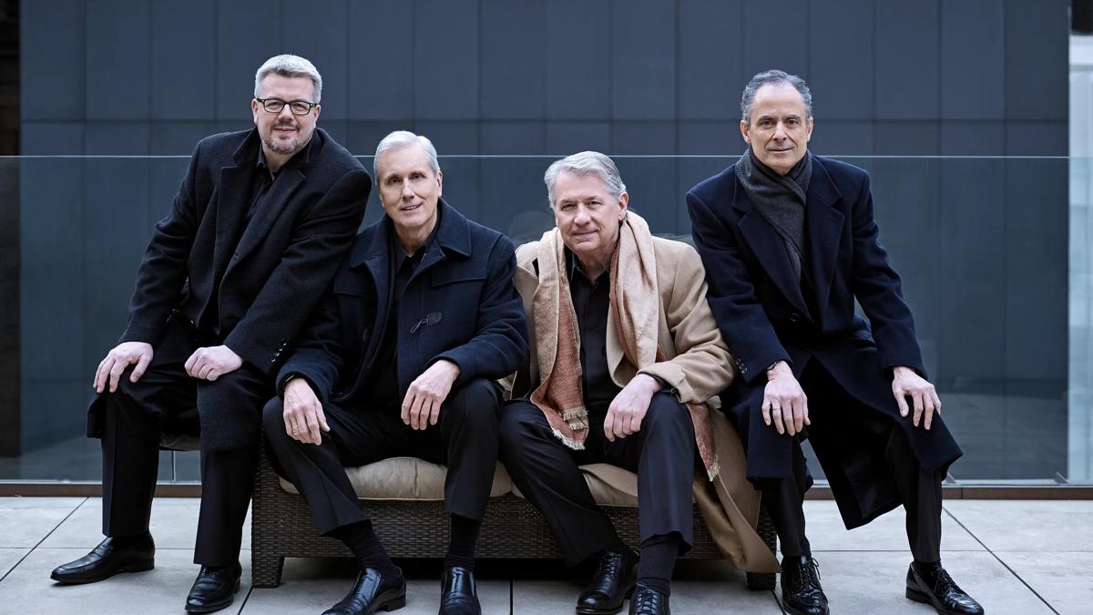 Emerson String Quartet performers in a winter coat sitting on a sofa
