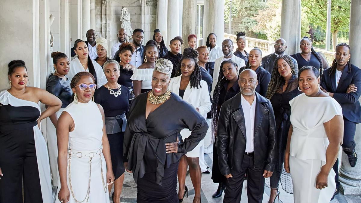 The 30 or so singers of the Kingdom Choir stand on a portico, all dressed up in black and white clothes