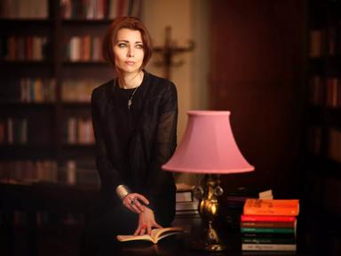 Elif Shafak standing in a library next to a pink lamp