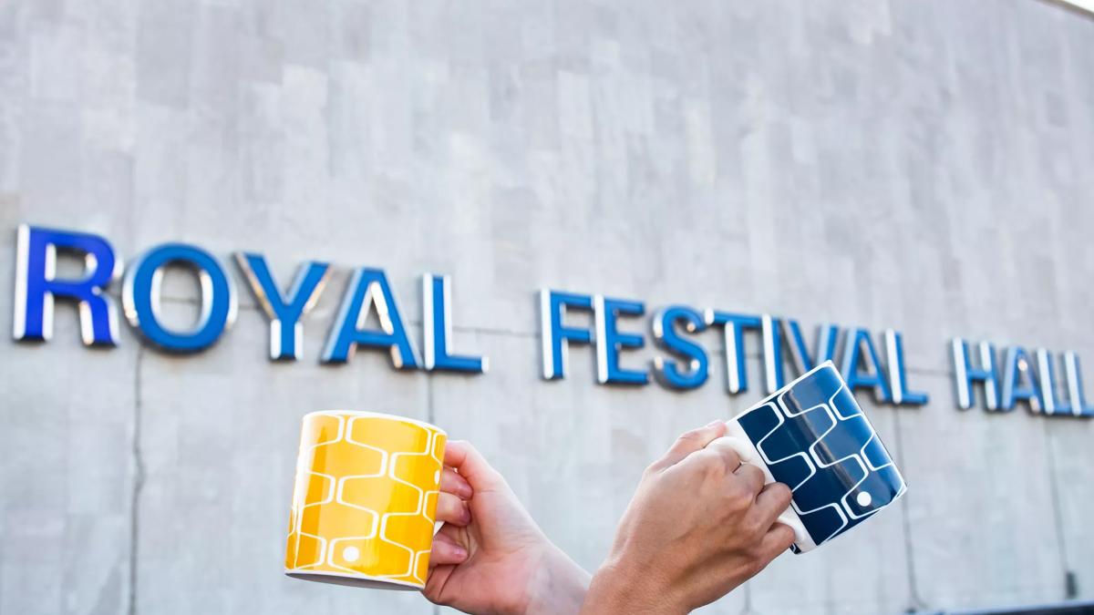Two Net & Ball mugs held in front of Royal Festival Hall signage