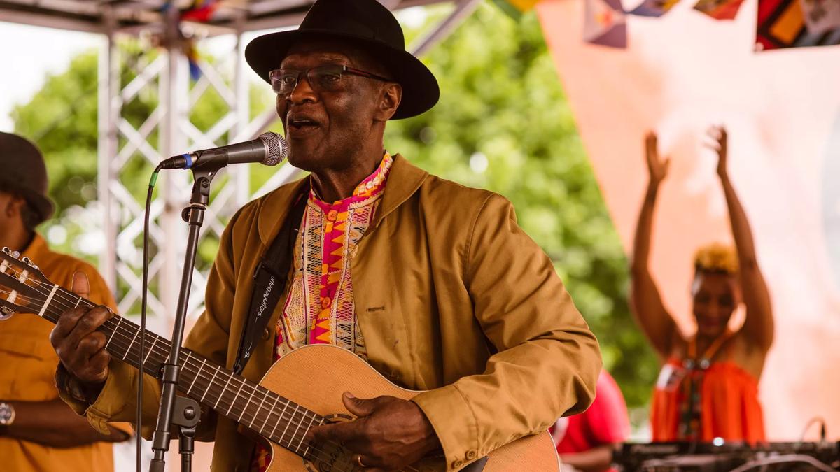 A man playing a guitar and singing for carnival at the Southbank Centre
