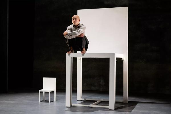 A man sits on a very large white chair