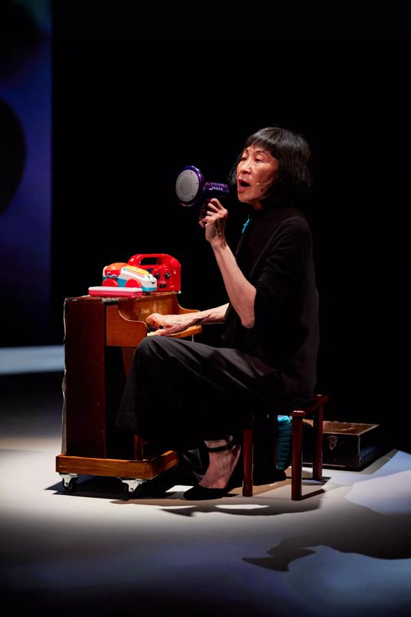 Margaret Leng Tan playing a toy piano and holding a toy megaphone