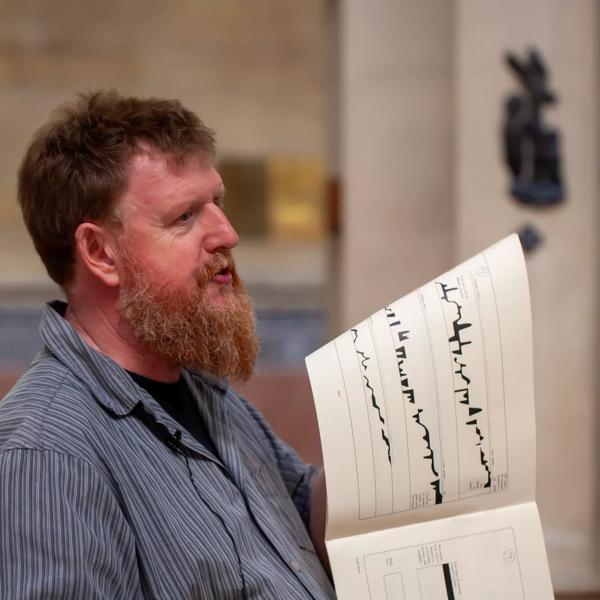 Duncan Chapman holding a visual notation score of score of Volumina by Ligeti 