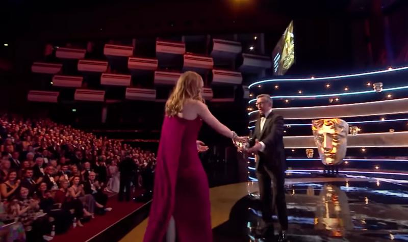 Jodie Comer walking onto the Royal Festival Hall stage at the 2019 BAFTA TV Awards to collect her award for Leading Actress from Steve Coogan