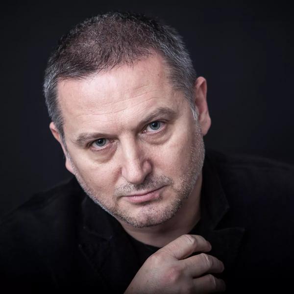 Georgi Gospodinov, a white man with grey shaven hair wears a black jumper on a black background