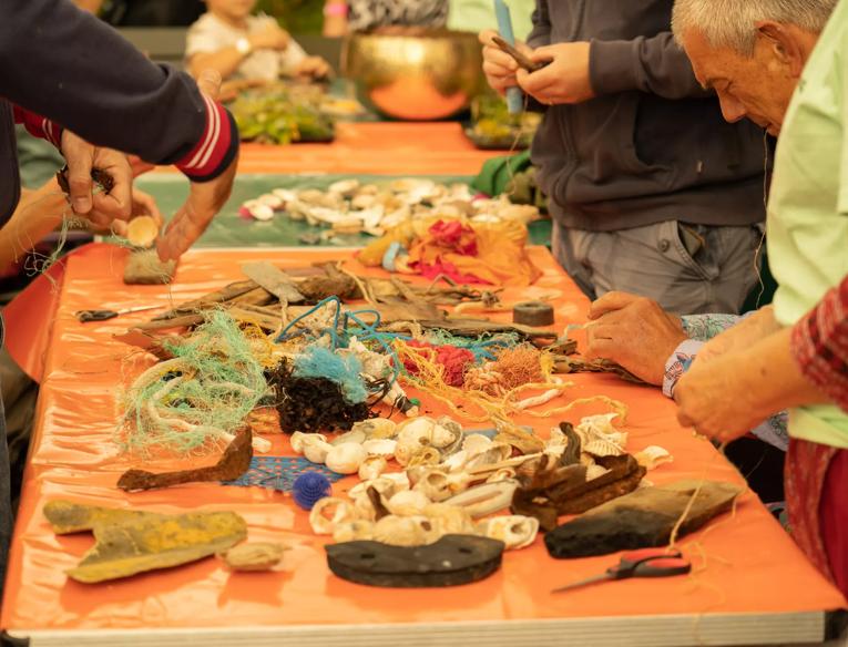 A group of people explore a table full of materials like wood and plastic 