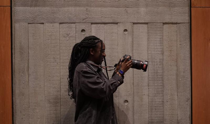 Side profile of a black woman holding a digital SLR 