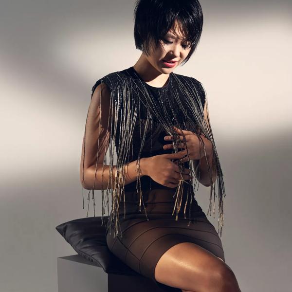 Yuja Wang sitting on a stool with dangles on her dress