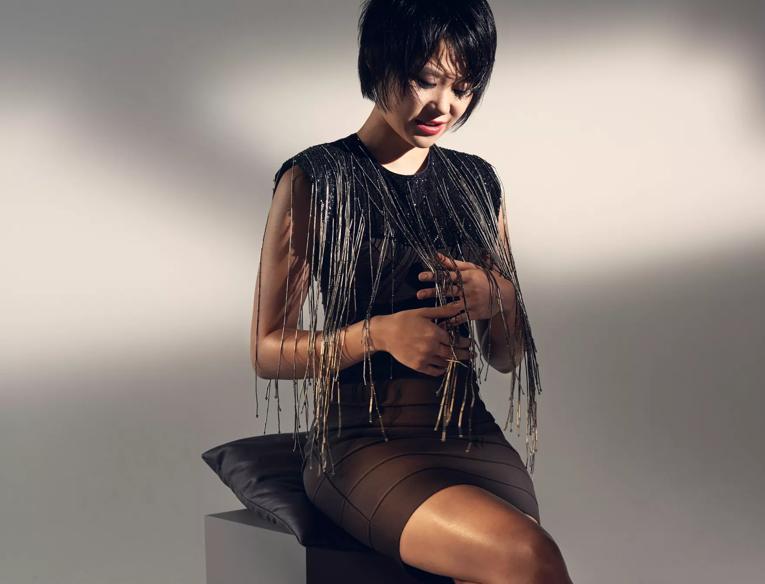 Yuja Wang sitting on a stool with dangles on her dress