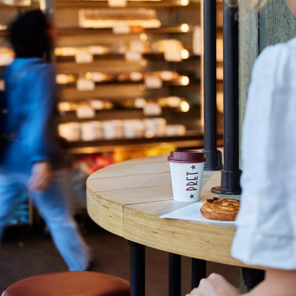 Pret A Manger interior with customer, coffee, and pastry in focus 