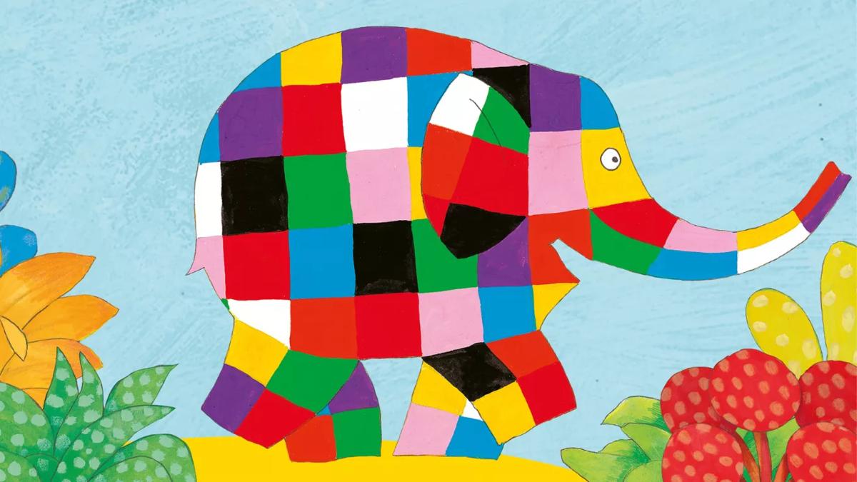 a large elephant covered in multicoloured square patches walks happily through flowers