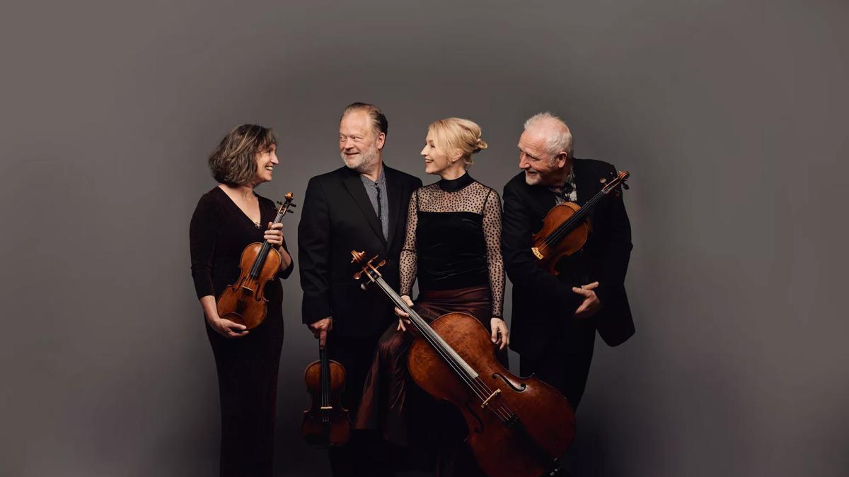 Brodsky Quartet smiling at each other whilst holding their instruments.