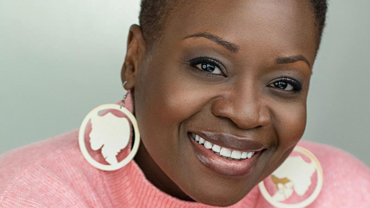 portrait of author Onyeka wearing large statement earrings and a pink jumper 