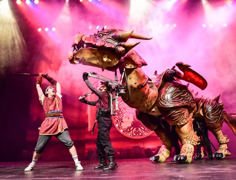 A man fights a dragon on stage