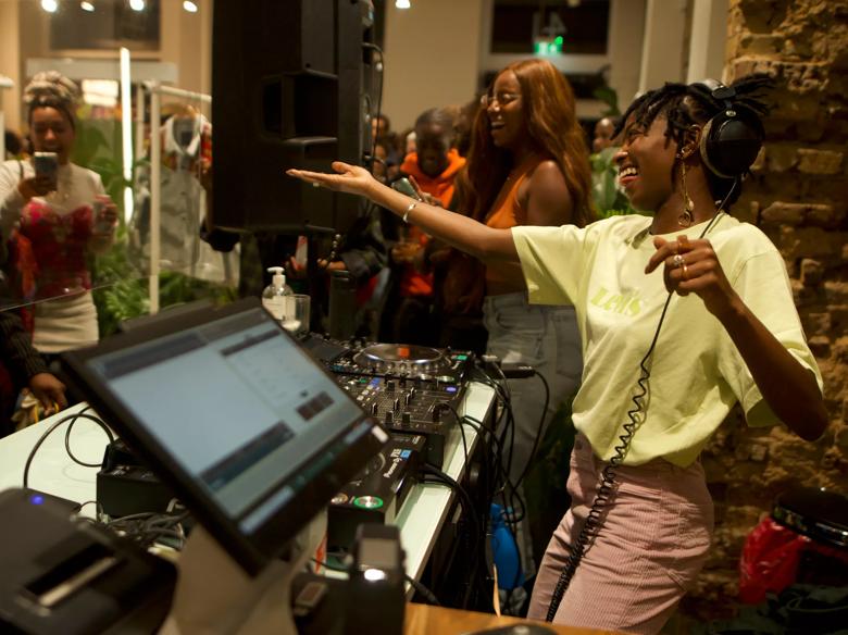 female DJ is laughing behind DJ decks in a crowded party 