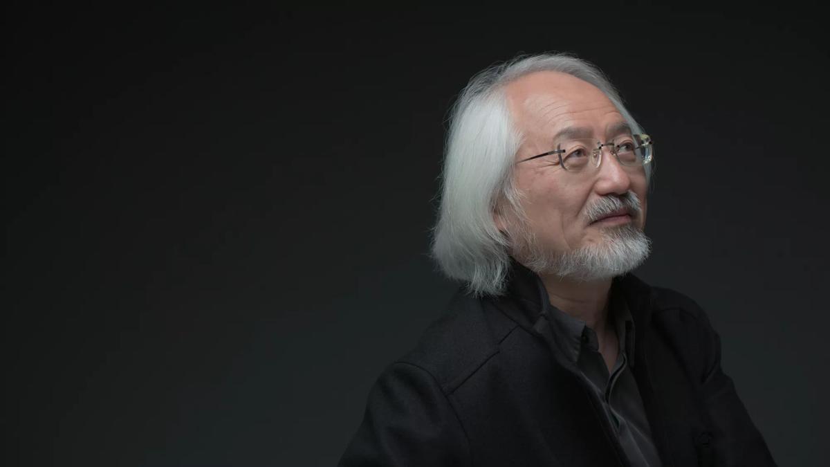 Head & shoulders portrait of conductor Masaaki Suzuki in a dark room