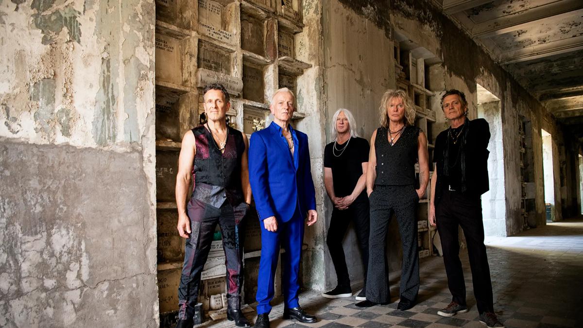 The 5 members of Def Leppard pose in a once grand but now dilapidated corridor, looking older but still 100% rock'n'roll