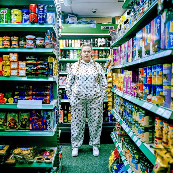 A woman in a Louis Vuitton tracksuit, standing in a supermarket 