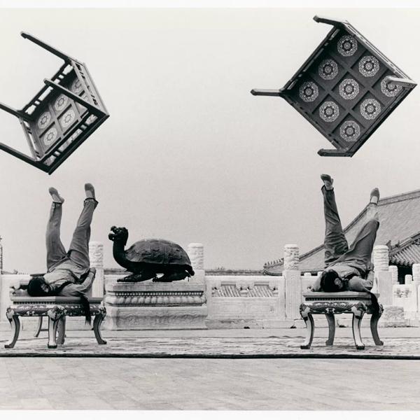 Black and White Photograph of two gymnasts throwing tables in the air with their feet