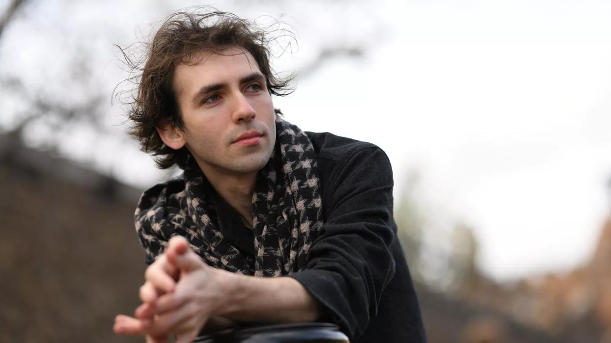 Alexandre Kantorow wearing a houndstooth scarf and staring into the distance