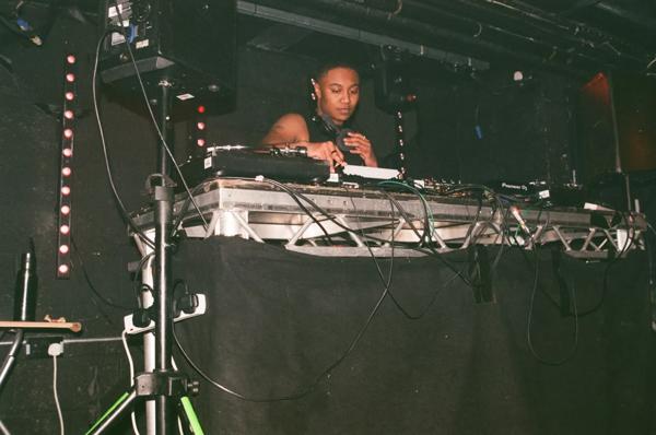 Photo of the DJ Rabz in front of decks with headphones round their neck. 