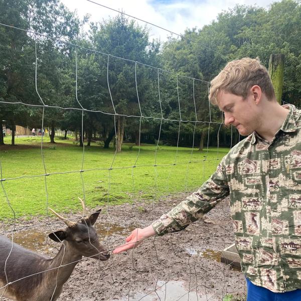 James Acaster feeding a goat through a wire fence 
