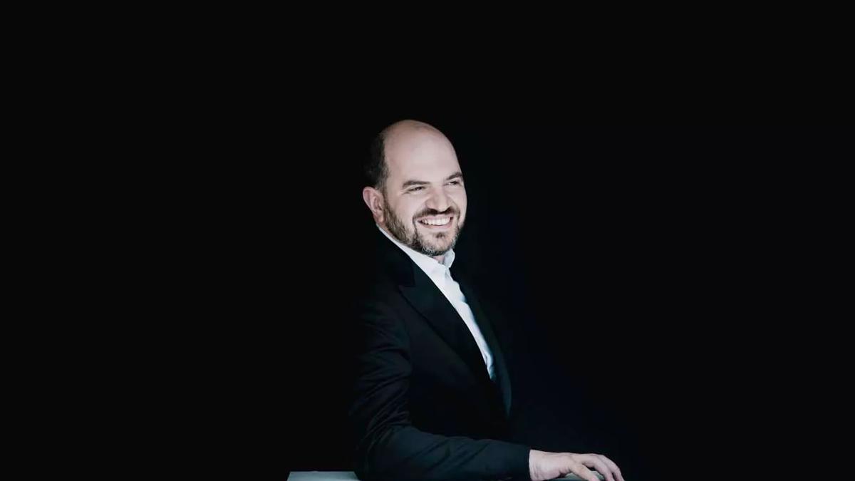 Pianist Kirill Gerstein smiling in a black suit
