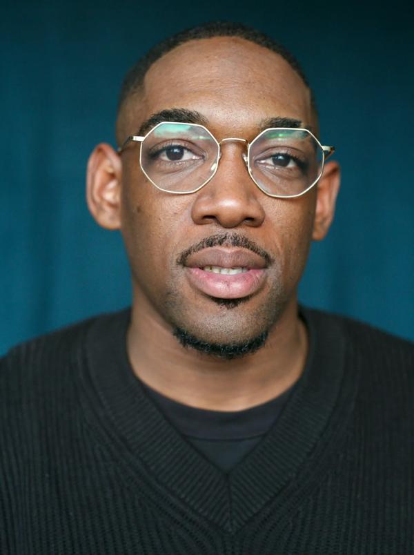 Portrait of DJ in black jumper with glasses on.