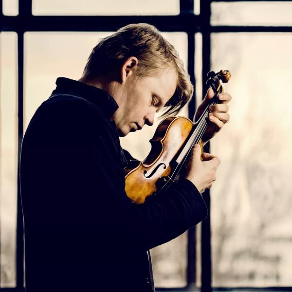 Violinist Pekka Kuusisto holding a violin close to his face