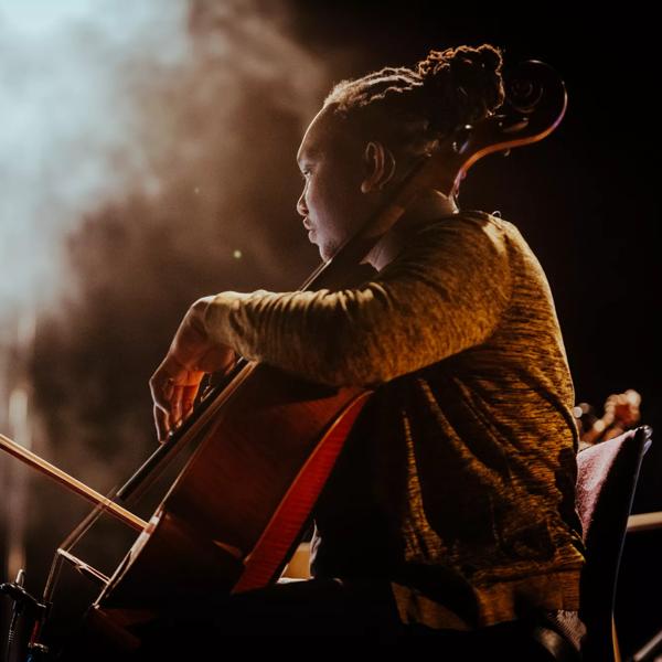 Cellist Abel Selaocoe playing on stage with the Manchester Collective