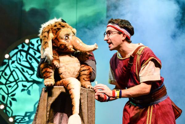 A man speaks with a puppet animal on stage