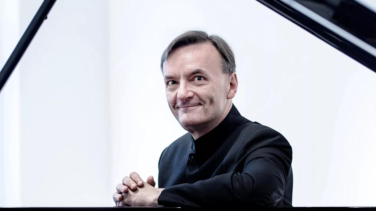 Pianist Sir Stephen Hough looking jolly in a black suit 