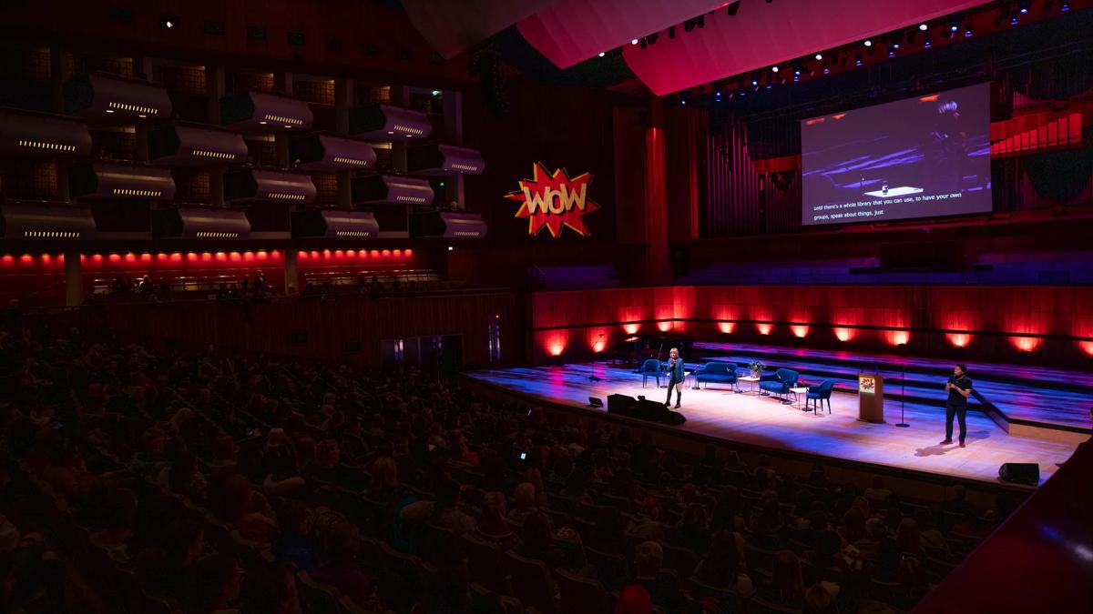Jude Kelly on a stage at the Royal Festival Hall, A large screen at the back of the hall and WOW logo on the side