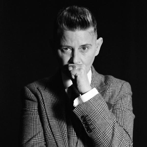 Black and white photo of author Joelle Taylor looking at the camera wearing a checkec suit