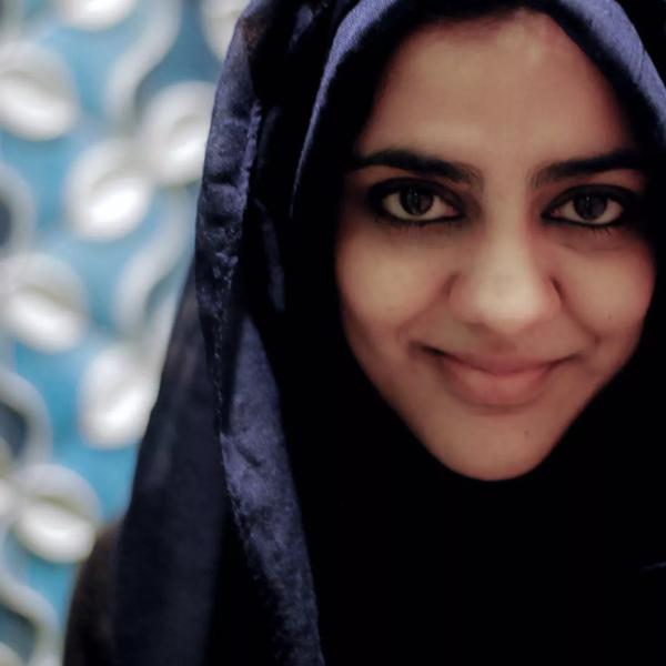 Children's author Zanib Mian smiling at the camera in a head piece