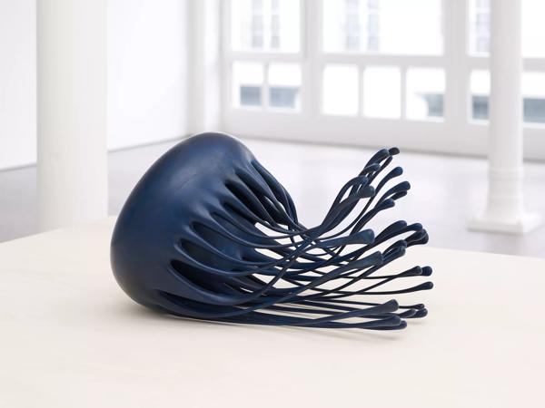 Navy blue jellyfish sculpture lays on a flat white surface